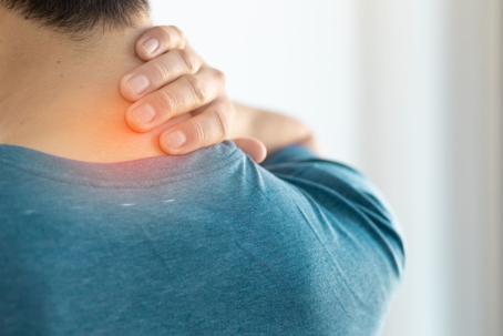 Man clutches his neck in pain